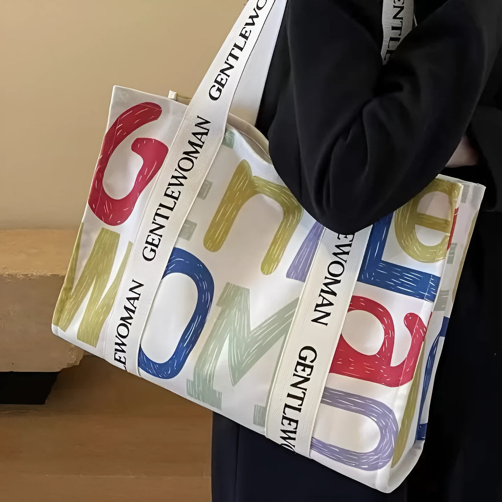 Large canvas women's tote bag with printed design, shown in shopping and travel use contexts.