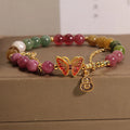 Natural jade coloured agate bracelet with a butterfly gourd tourmaline charm on an elasticated cord.