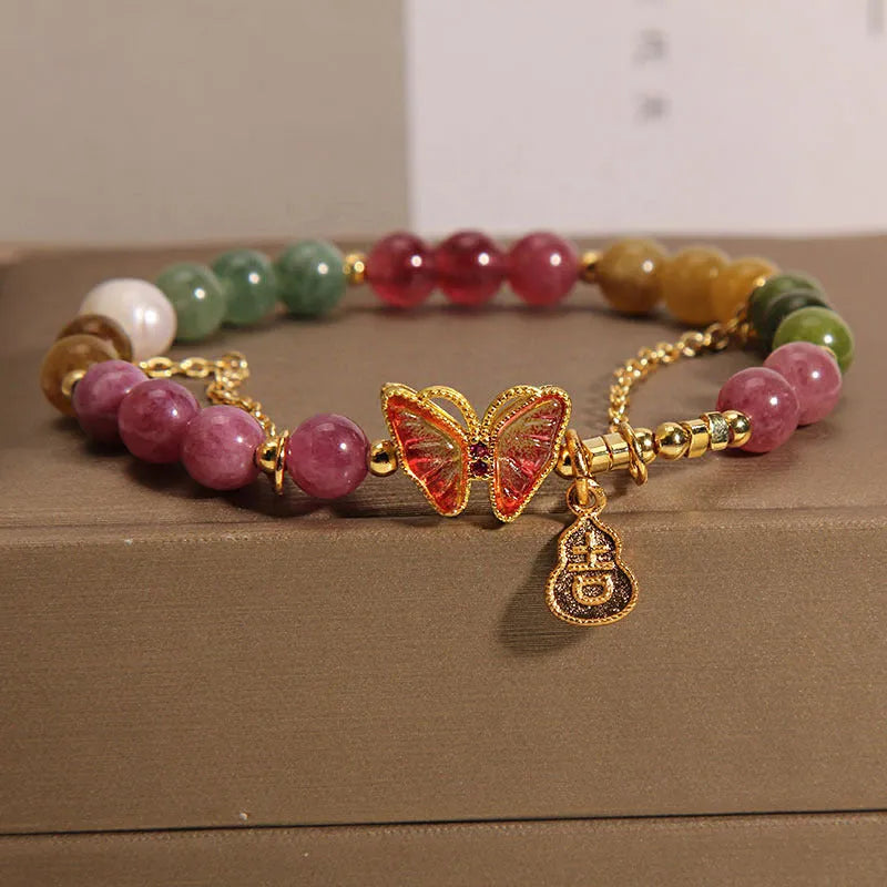 Natural jade coloured agate bracelet with a butterfly gourd tourmaline charm on an elasticated cord.