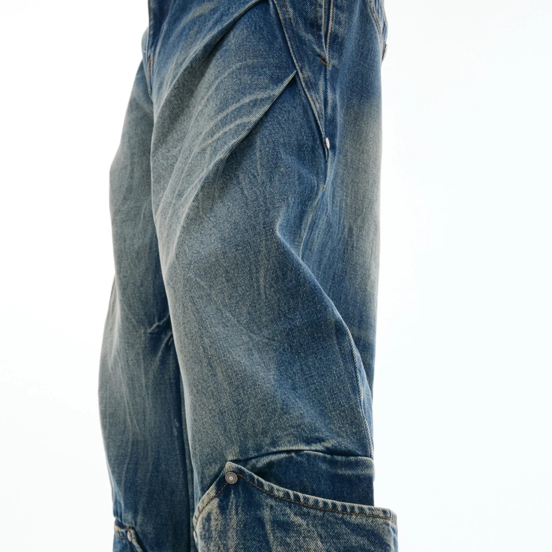 Man wearing verdant blue loose-fit jeans with curved seam detail and a vintage washed burst pattern.