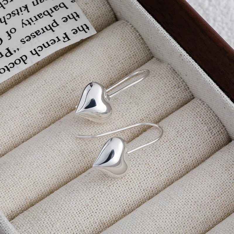 Silver glossy heart-shaped Korean-style earrings with a three-dimensional design on a white background.