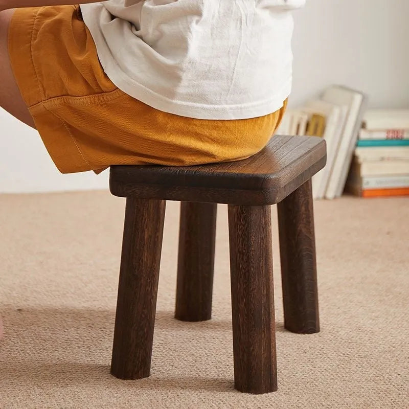 Distressed solid wood stool for changing shoes with a bracket frame structure.