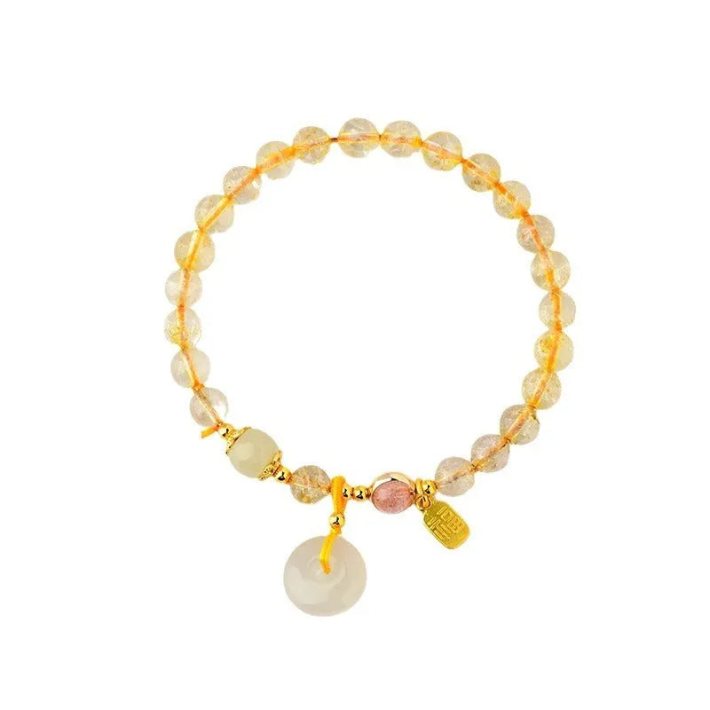 Gold rutilated quartz bracelet with a peace buckle pendant and geometric safety clasp.