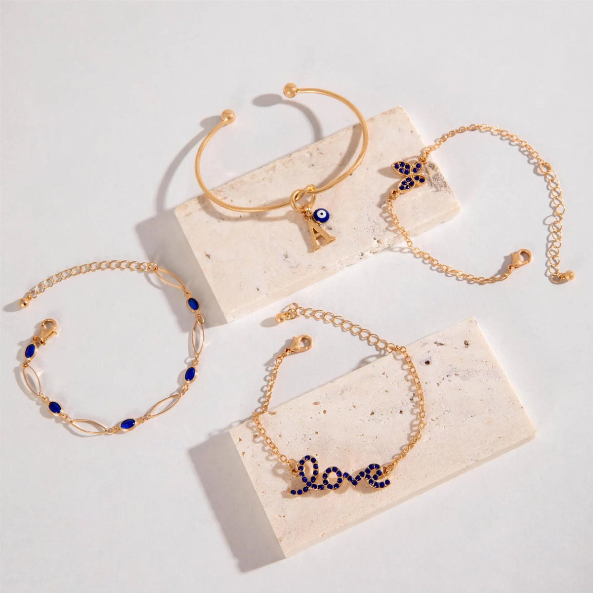 Four-piece blue and gold-tone bracelet set with heart, butterfly, and flower designs, rhinestone accents, alloy electroplated finish