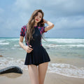Women's black flower pattern one-piece swimsuit with long sleeves and a tight, dress-style fit.