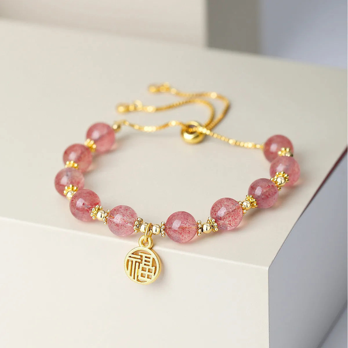 Women's Strawberry Quartz crystal bracelet with geometric shape and fu character design on an electroplated chain.