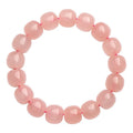 Pink natural crystal bracelet with barrel-shaped beads on a wrist.