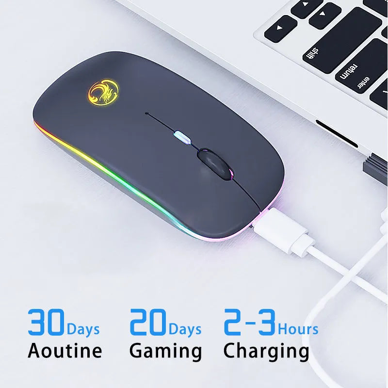 White dual-mode wireless mouse with silent buttons on a wooden desk next to a laptop.