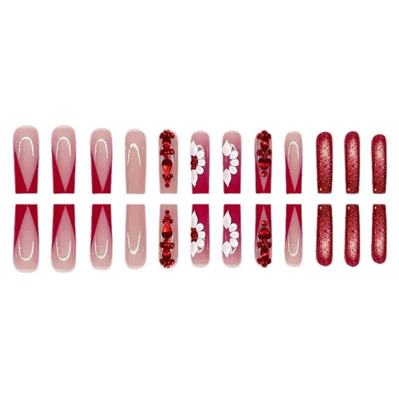Long almond-shaped false nails with red diamond and floral art in sweet style.