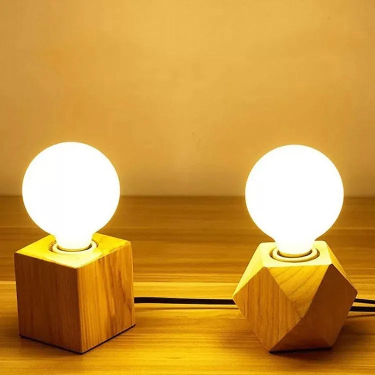Retro-style square wooden lamp holder on a table next to a power cord.