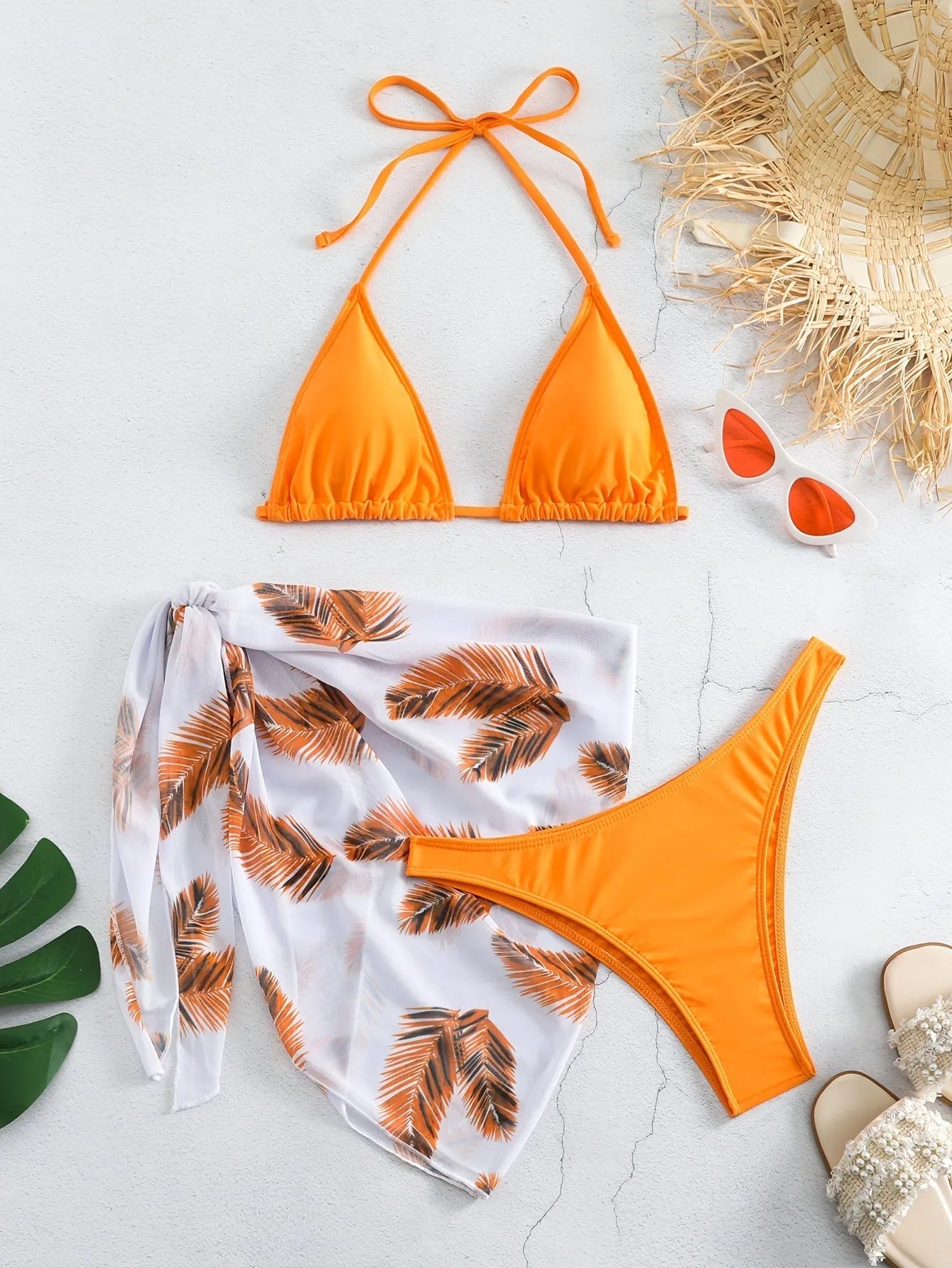Women's orange polyester bikini set with a matching printed gauze skirt laid flat.