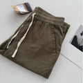 Man wearing beige loose-fit straight-leg casual trousers with a drawstring waistband.