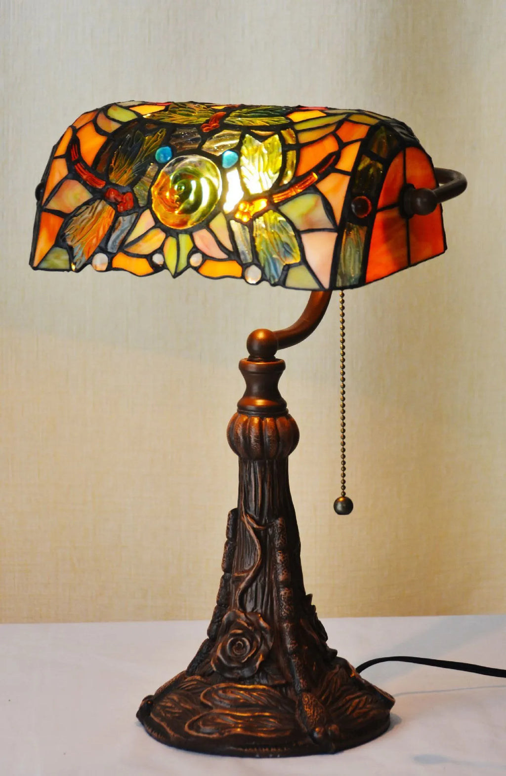 A 10-inch tall Tiffany-style table lamp with a stained glass shade on a resin base, shown on a desk.