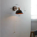 Nordic bedside wall lamp in walnut wood colour on a bedroom wall.