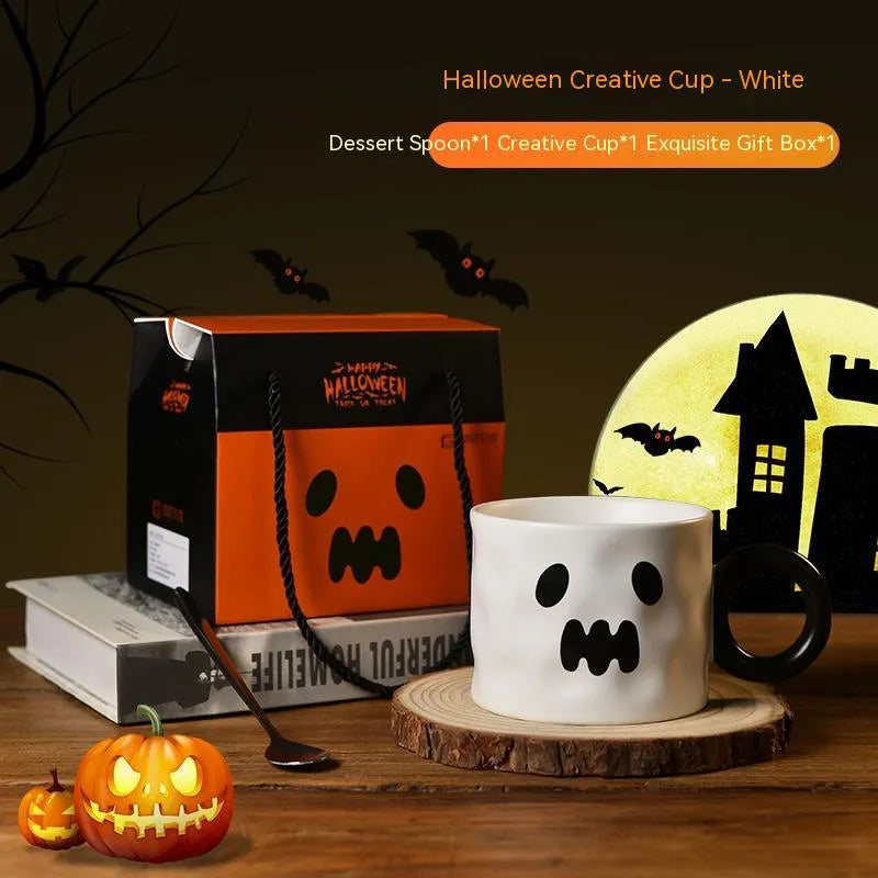 Orange ceramic pumpkin-shaped mug with handle on a table beside a dessert spoon and gift box.