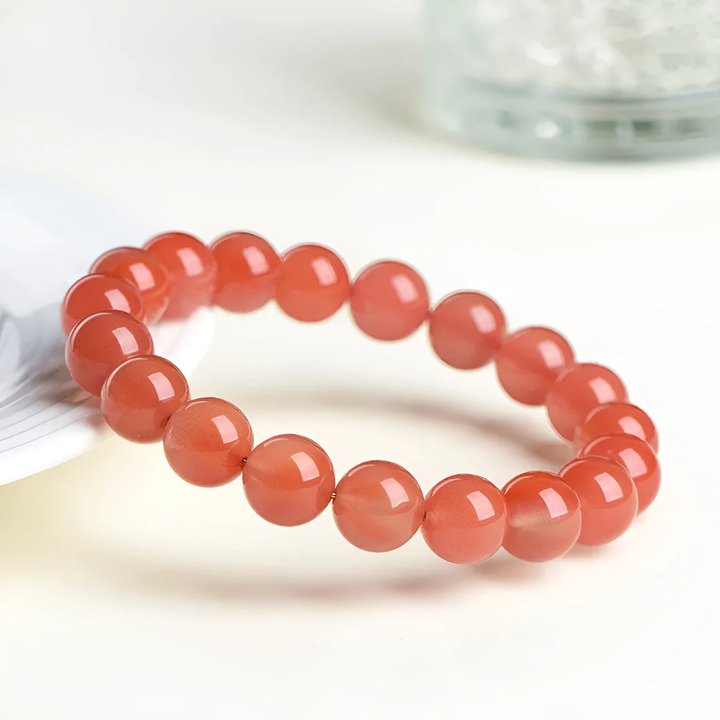 Natural cherry red agate beaded bracelet showing polished stones on a wrist, demonstrating single and triple strand options.