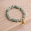 Women's strawberry quartz bracelet with lucky cat charm on grey background