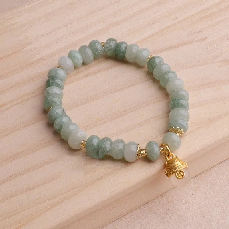 Women's strawberry quartz bracelet with lucky cat charm on grey background