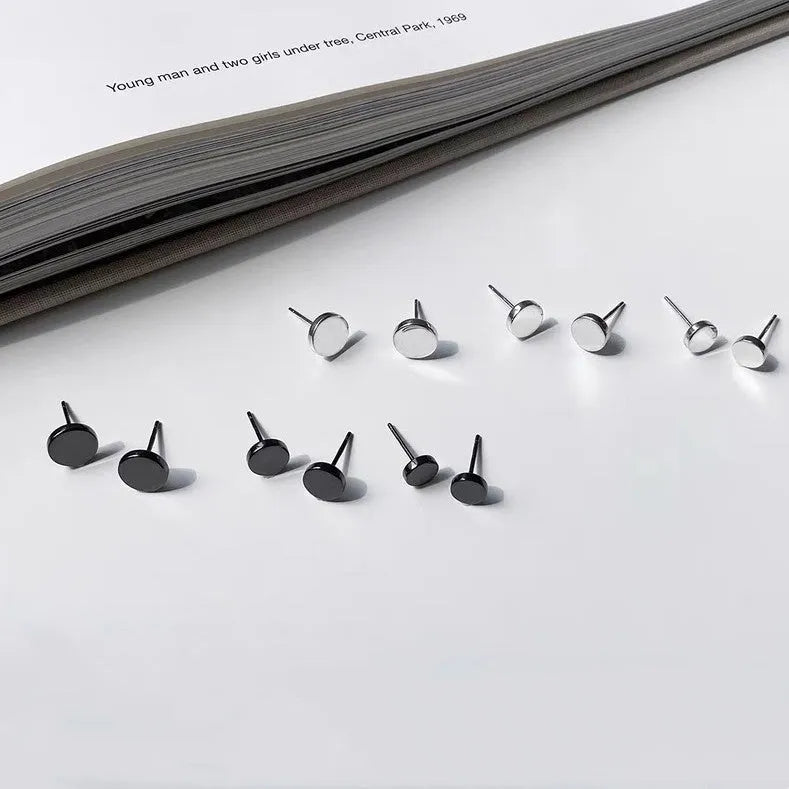 A pair of simple round flat stud earrings in sterling silver, shown in silver and black finishes.