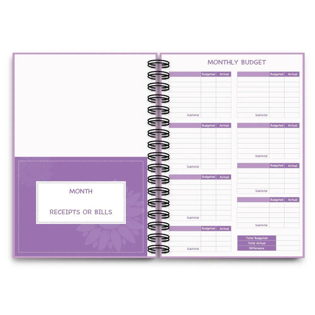 J12 purple coil-bound financial planning notebook with pen, stickers, and paper clips on a desk.