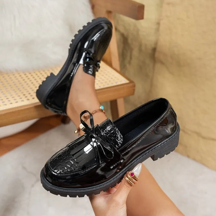 Women's black flat loafers with a decorative bow on the upper, made from artificial PU leather.