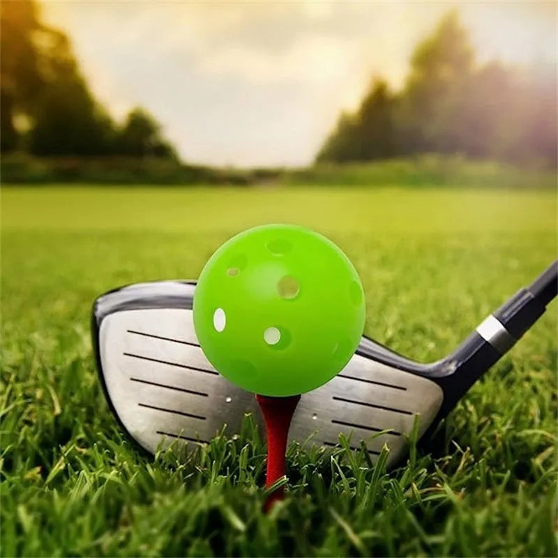 Six brightly coloured 42mm golf practice balls with a hole-patterned surface, laid out on a green net pocket.