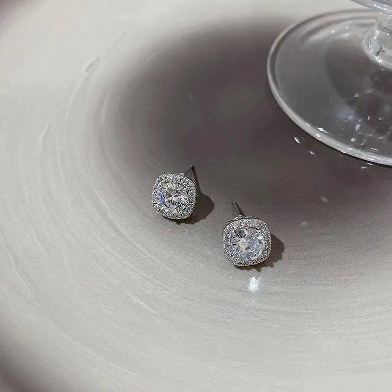 A pair of square geometric alloy earrings with diamond treatment in silver colour.