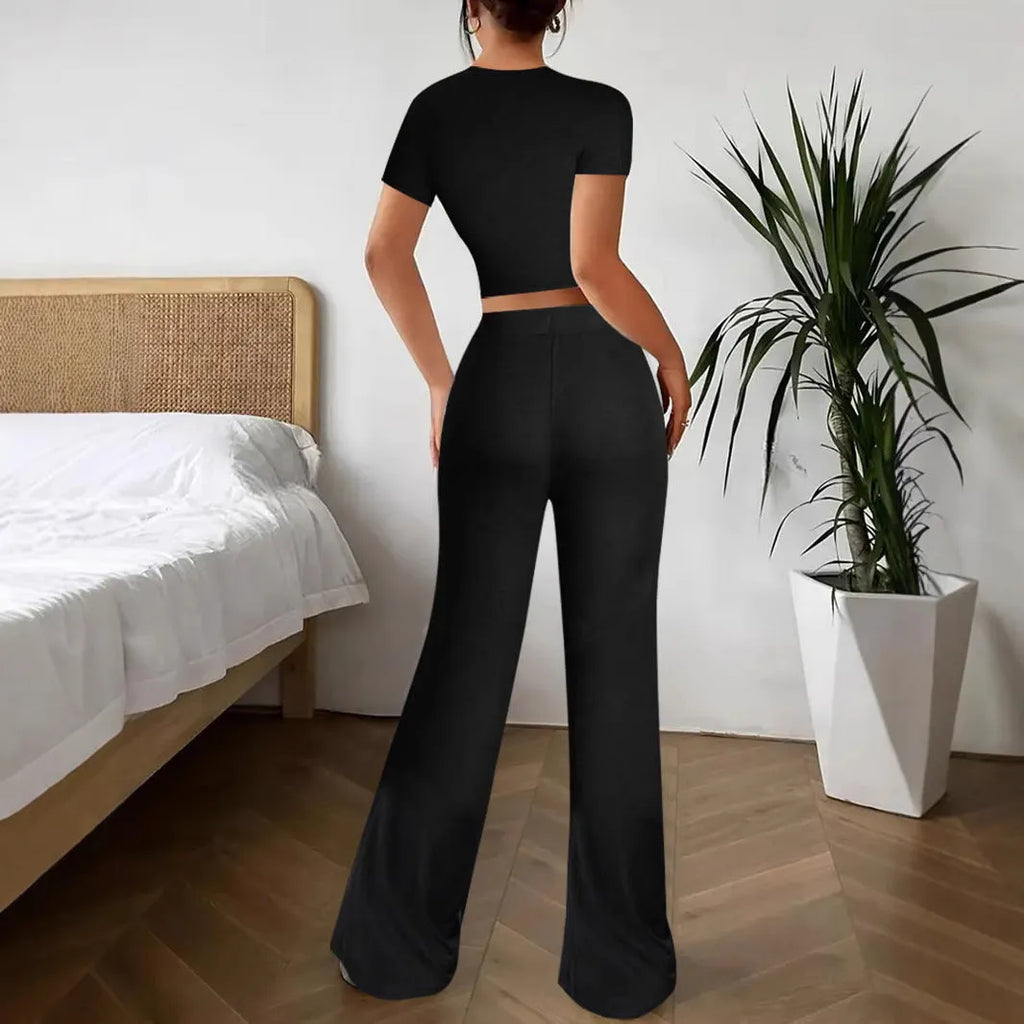 A woman's black high-waist trousers and matching short-sleeve T-shirt co-ord set laid flat.
