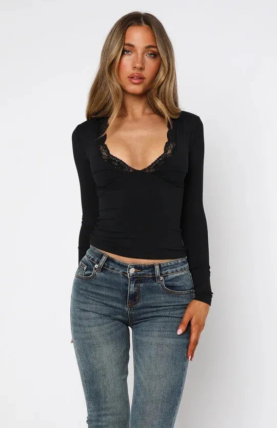 Women's black slim-fit long sleeve top with white lace flower decoration on the front.