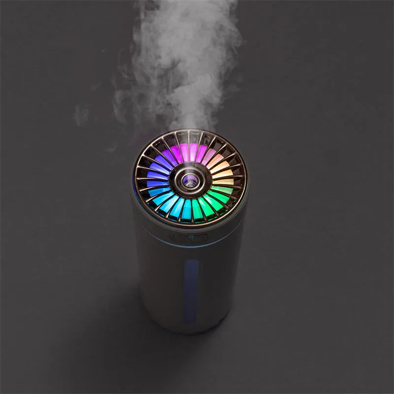 Black wireless USB car humidifier with colourful LED lights on a desktop next to a cup holder.