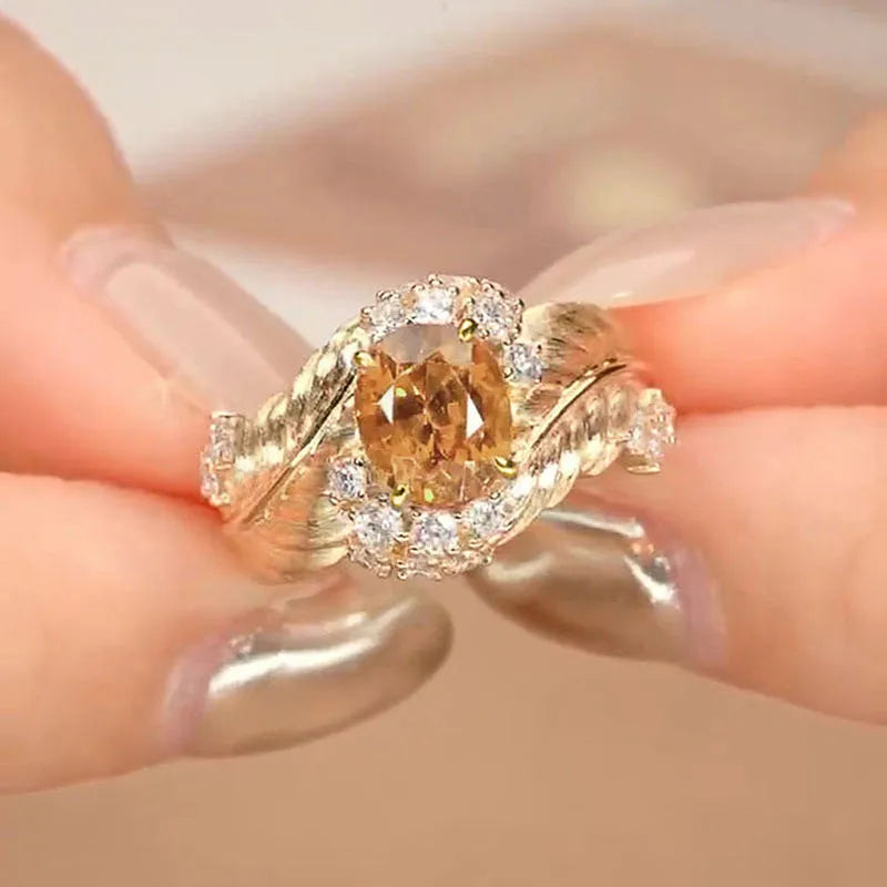 Gold-coloured copper ring with embossed feather pattern and yellow zircon stone.