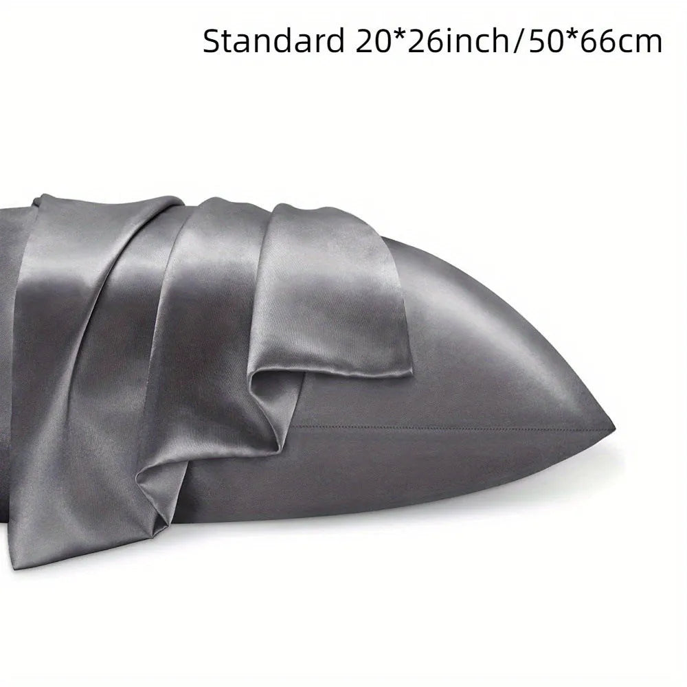 A pair of solid colour satin cloth pillowcases in a choice of sizes on a bed.