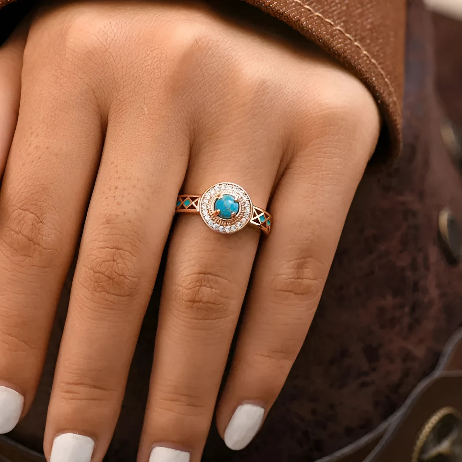 Rose gold women's ring with turquoise geometric centre and inlaid zircon stones on a finger.