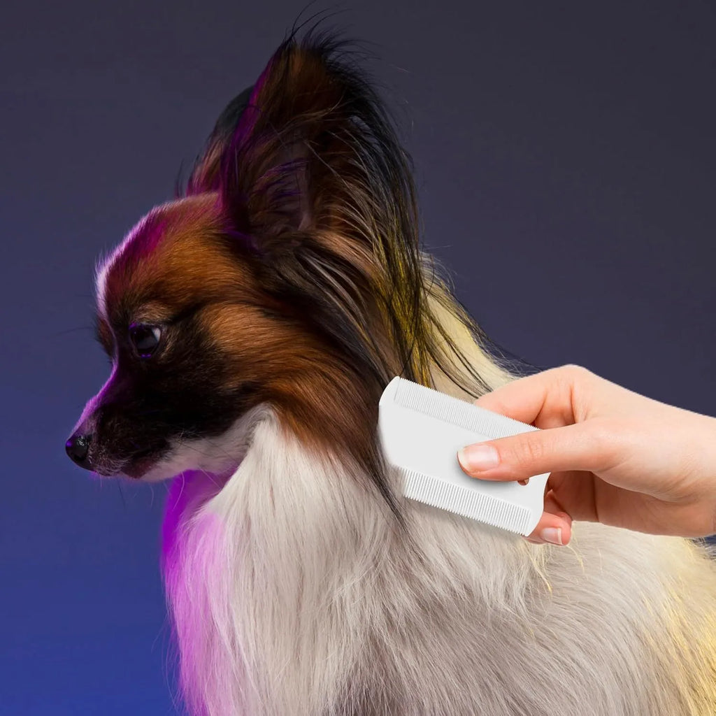 Small white double-sided plastic flea comb for dogs and cats on a blue background.